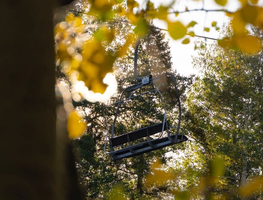 Chairlift seat visible through golden aspens.
